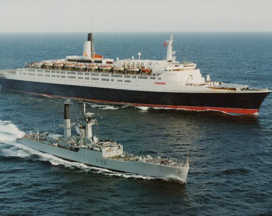 HMS Londonderry and QE2 in the ocean, celebrating QE2's return from the Falklands with a twenty-one-gun salute