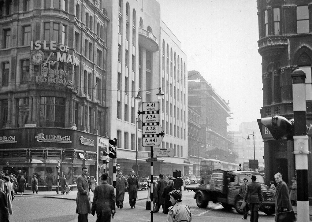 intage black and white image showing pedestrians in Birmingham city center at the intersection of New Street and Corporation Street.