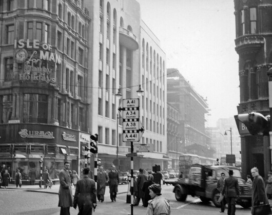 intage black and white image showing pedestrians in Birmingham city center at the intersection of New Street and Corporation Street.