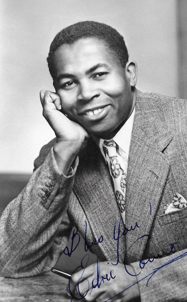 Black and white signed photo of Edric Connor, dressed in a suit, exuding sophistication.