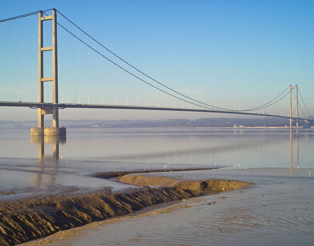 Scenic view of the Humber Bridge from the shore, highlighting its architectural beauty against a tranquil landscape.