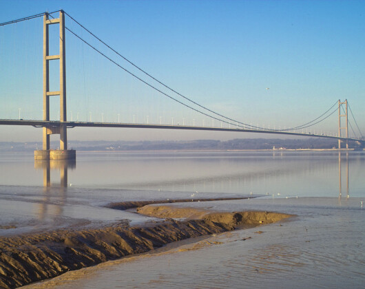 Scenic view of the Humber Bridge from the shore, highlighting its architectural beauty against a tranquil landscape.