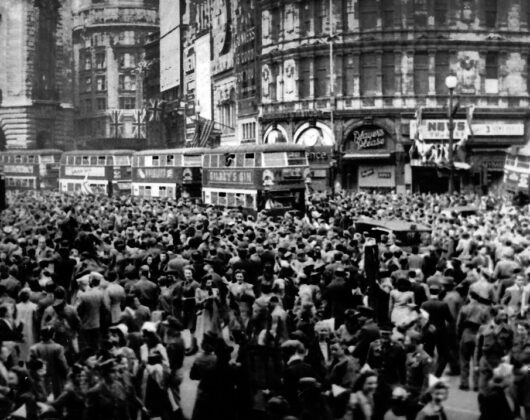 A lively crowd fills Piccadilly, London, during VE Day celebrations, showcasing a festive spirit in the city street.
