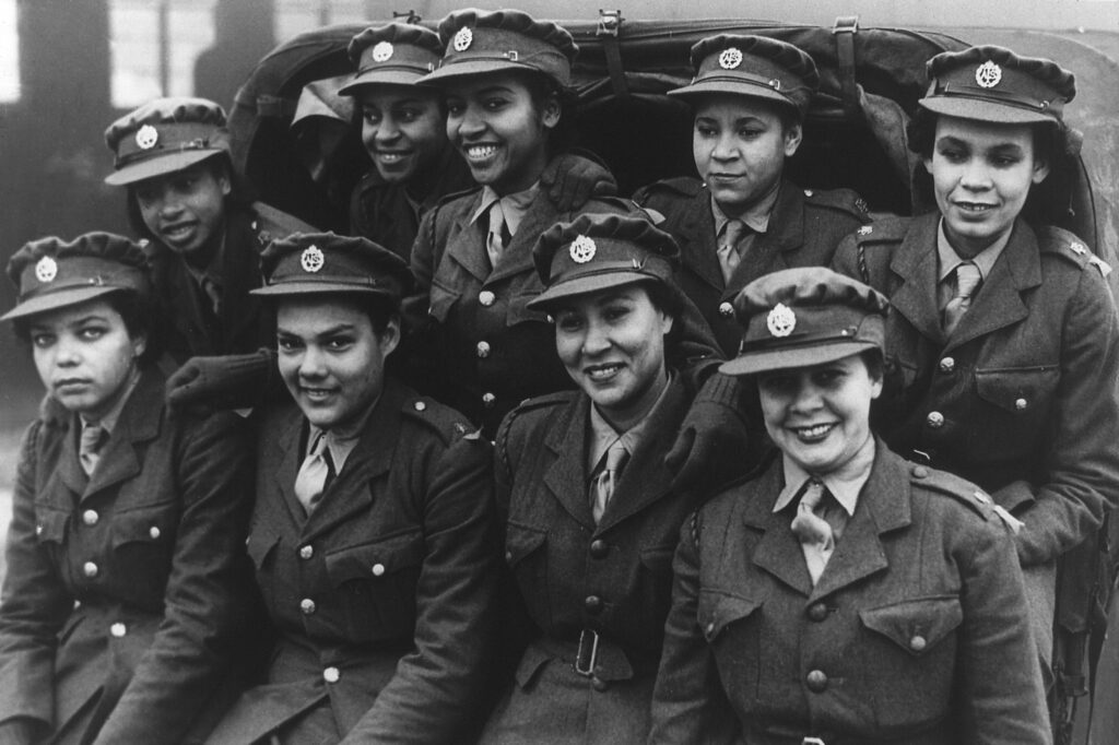 West Indian ATS recruits in uniform seated in a truck, marking their arrival at training camp in 1943.