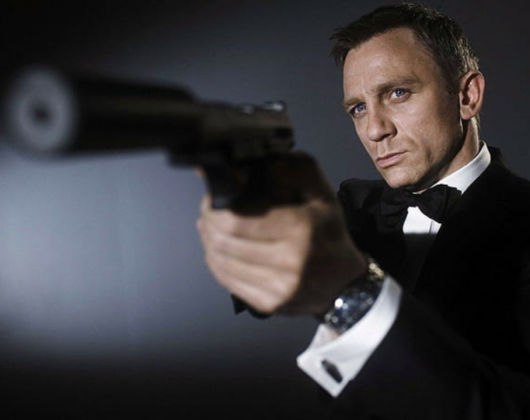 James Bond, portrayed by Daniel Craig, stands in a tuxedo with a gun, embodying sophistication and danger.